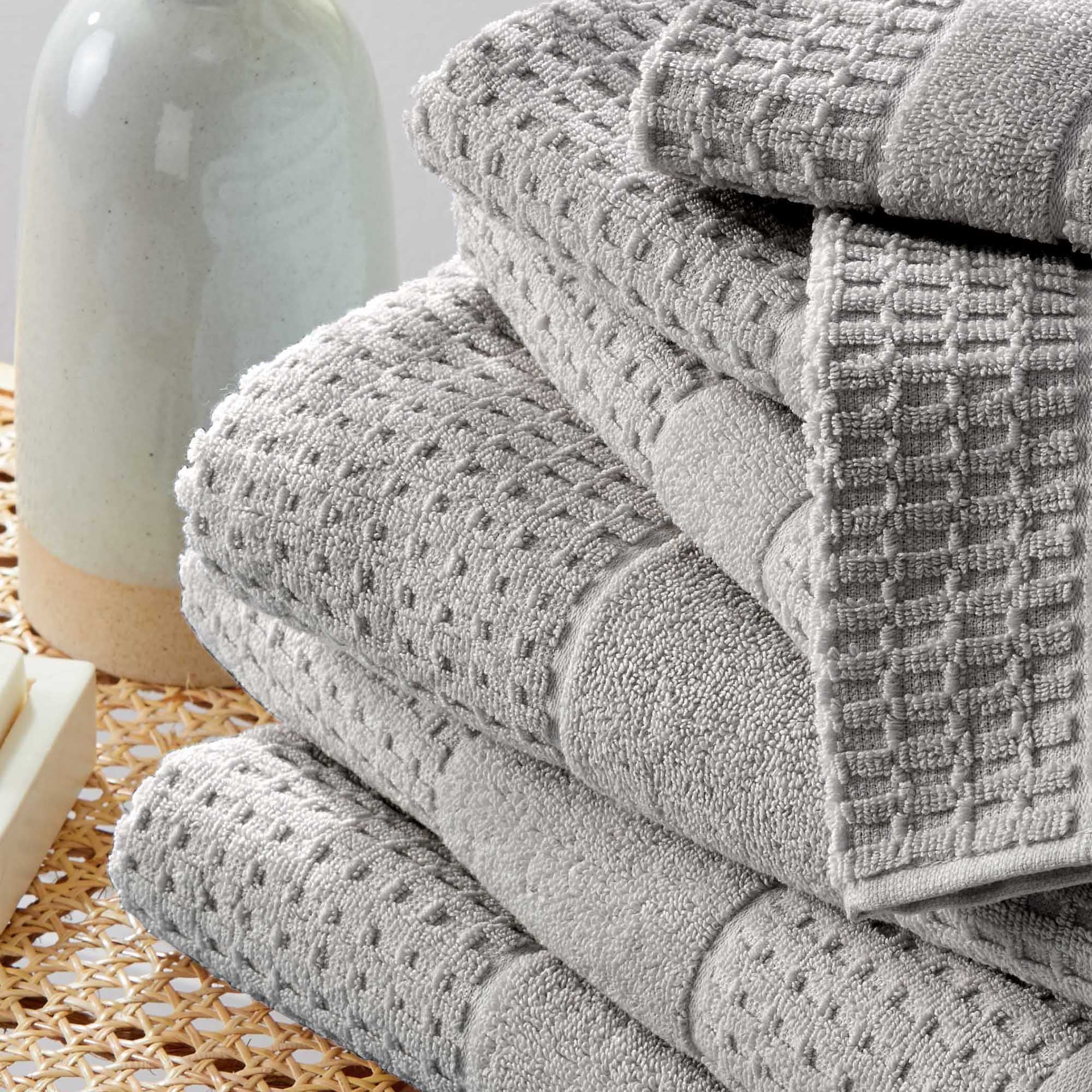 Harper Collection Waffle Textured Bath Towels by Market & Place featuring premium 100% cotton construction with a stylish waffle weave texture. Available in multiple colors and set configurations, including bath towels, hand towels, and washcloths, shown folded, stacked, and styled to highlight their soft, plush, and highly absorbent design.