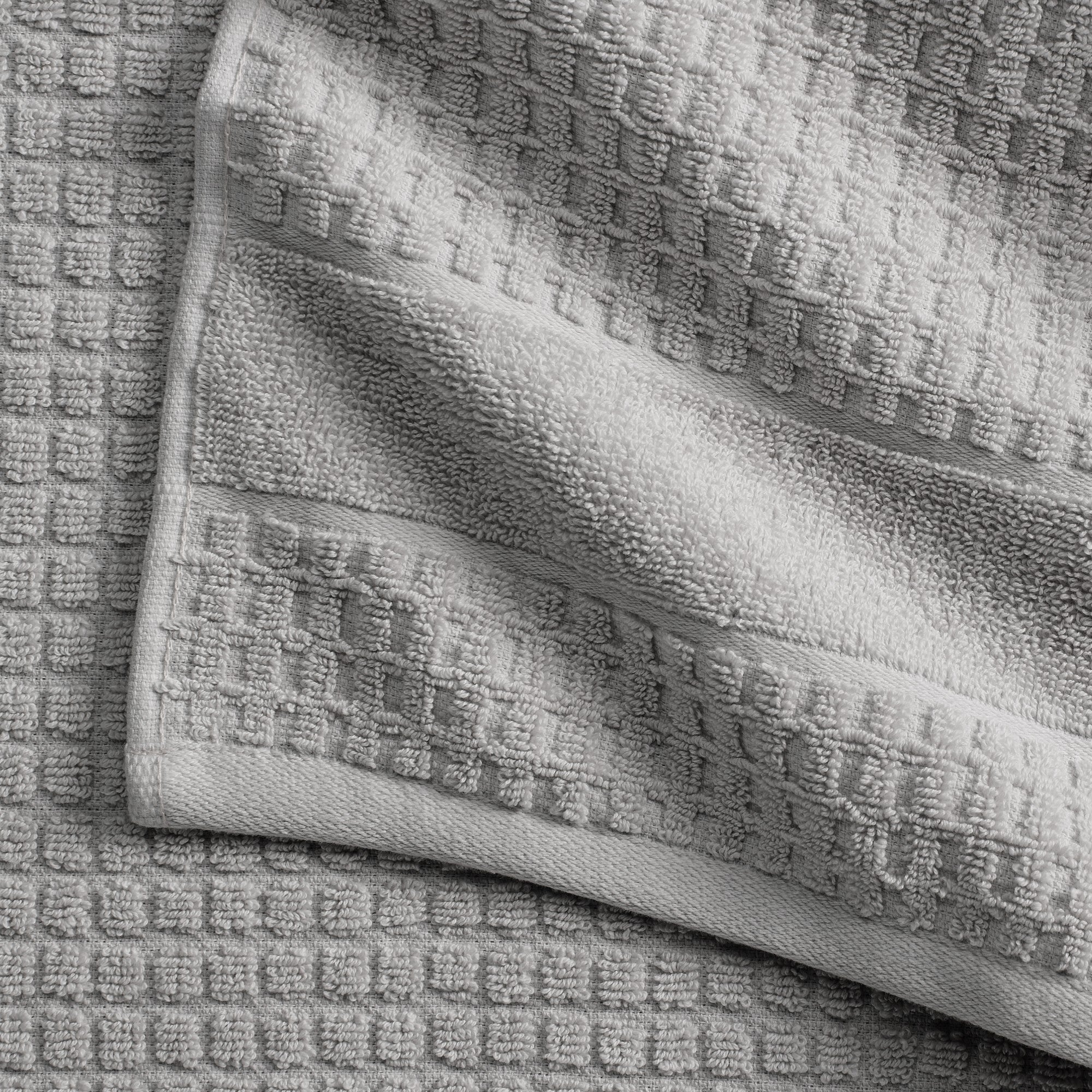 Harper Collection Waffle Textured Bath Towels by Market & Place featuring premium 100% cotton construction with a stylish waffle weave texture. Available in multiple colors and set configurations, including bath towels, hand towels, and washcloths, shown folded, stacked, and styled to highlight their soft, plush, and highly absorbent design.