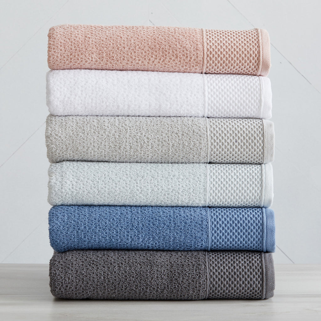 Soft and absorbent 100% cotton bath towel sets in assorted solid colors, featuring plush textures and coordinated bath towels, hand towels, and washcloths styled in bathroom and lifestyle settings.