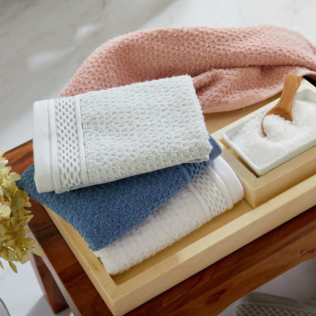 Soft and absorbent 100% cotton bath towel sets in assorted solid colors, featuring plush textures and coordinated bath towels, hand towels, and washcloths styled in bathroom and lifestyle settings.