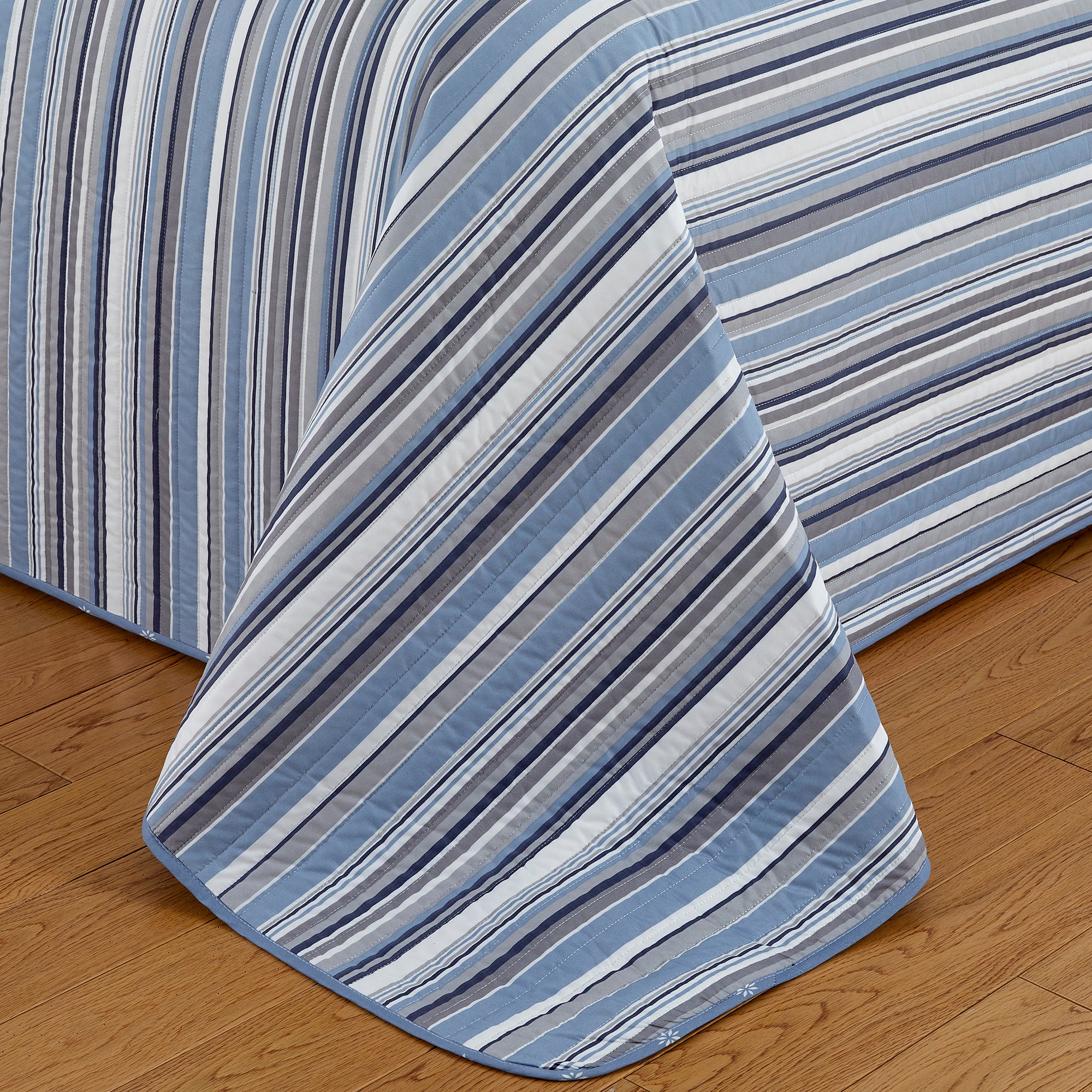 Elise Collection striped quilt set featuring classic blue and gray stripe patterns with a coordinating floral reverse, shown in multiple styling views and close-up detail shots. Soft, reversible bedding with matching shams, designed for year-round comfort and casual bedroom décor.