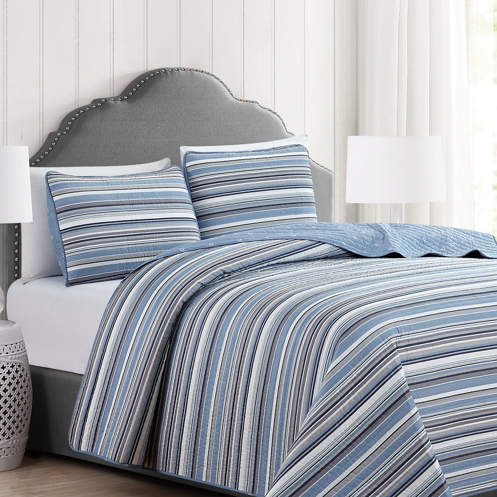 Elise Collection striped quilt set featuring classic blue and gray stripe patterns with a coordinating floral reverse, shown in multiple styling views and close-up detail shots. Soft, reversible bedding with matching shams, designed for year-round comfort and casual bedroom décor.