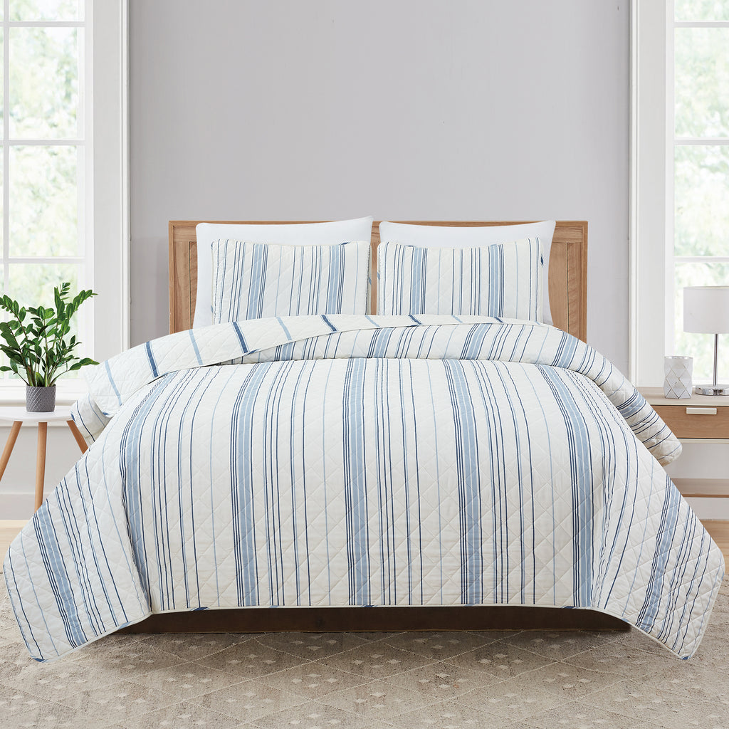 Sofia Collection striped quilt set featuring classic blue and white stripes with a reversible design, shown on beds and in close-up detail views. Soft, lightweight bedding with coordinating shams, styled in a bright and casual bedroom setting.