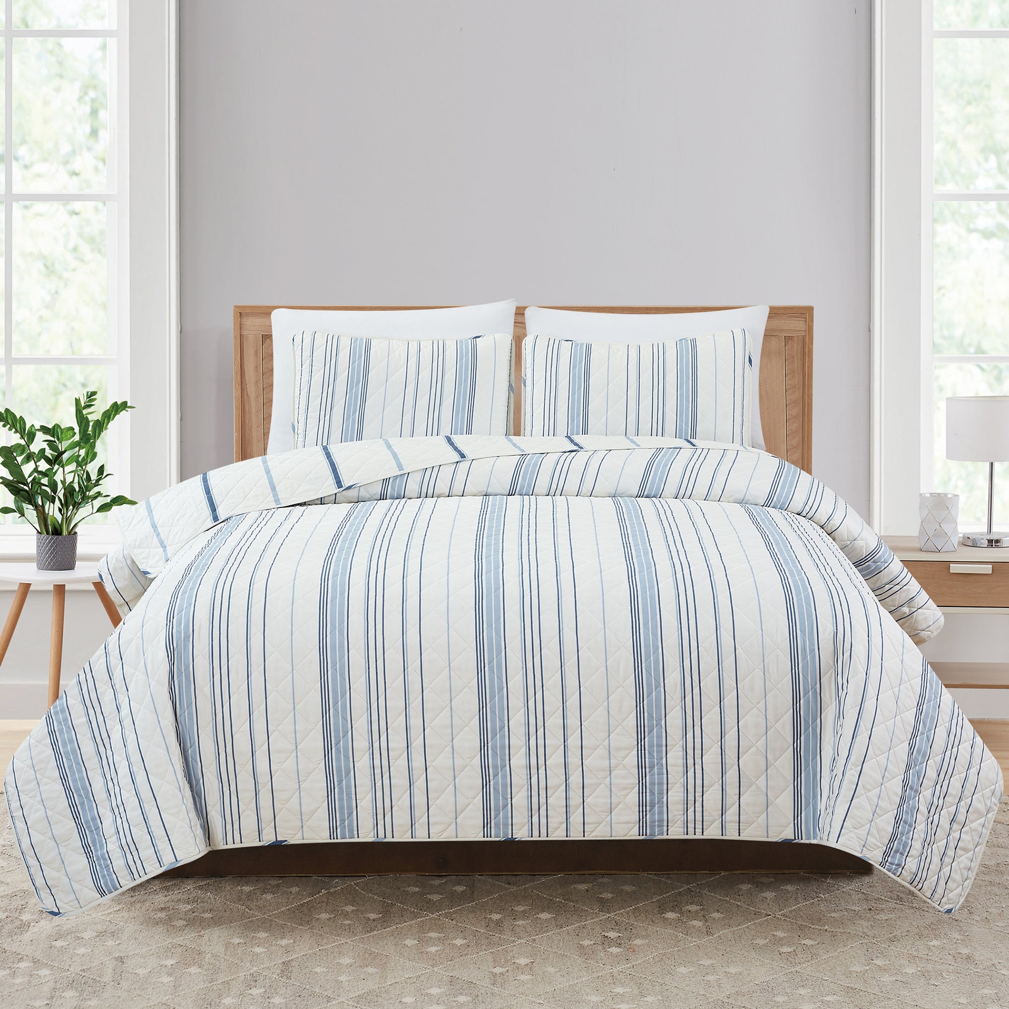 Sofia Collection striped quilt set featuring classic blue and white stripes with a reversible design, shown on beds and in close-up detail views. Soft, lightweight bedding with coordinating shams, styled in a bright and casual bedroom setting.