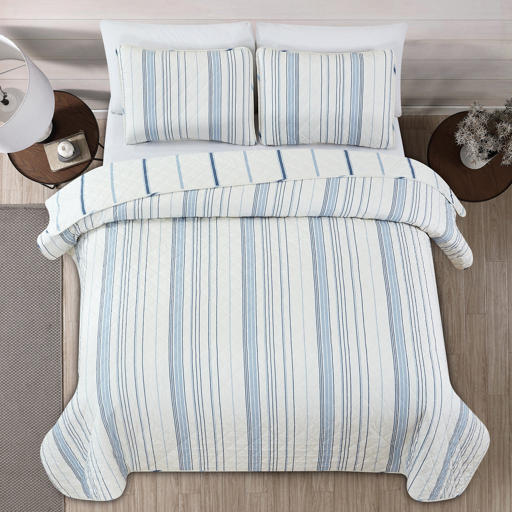 Sofia Collection striped quilt set featuring classic blue and white stripes with a reversible design, shown on beds and in close-up detail views. Soft, lightweight bedding with coordinating shams, styled in a bright and casual bedroom setting.
