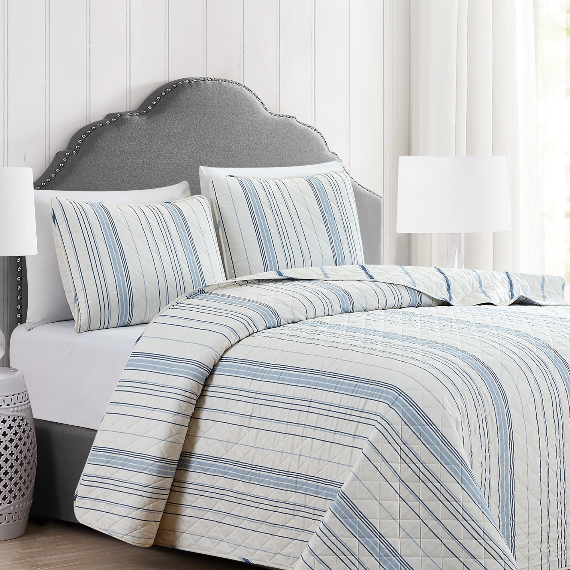 Sofia Collection striped quilt set featuring classic blue and white stripes with a reversible design, shown on beds and in close-up detail views. Soft, lightweight bedding with coordinating shams, styled in a bright and casual bedroom setting.