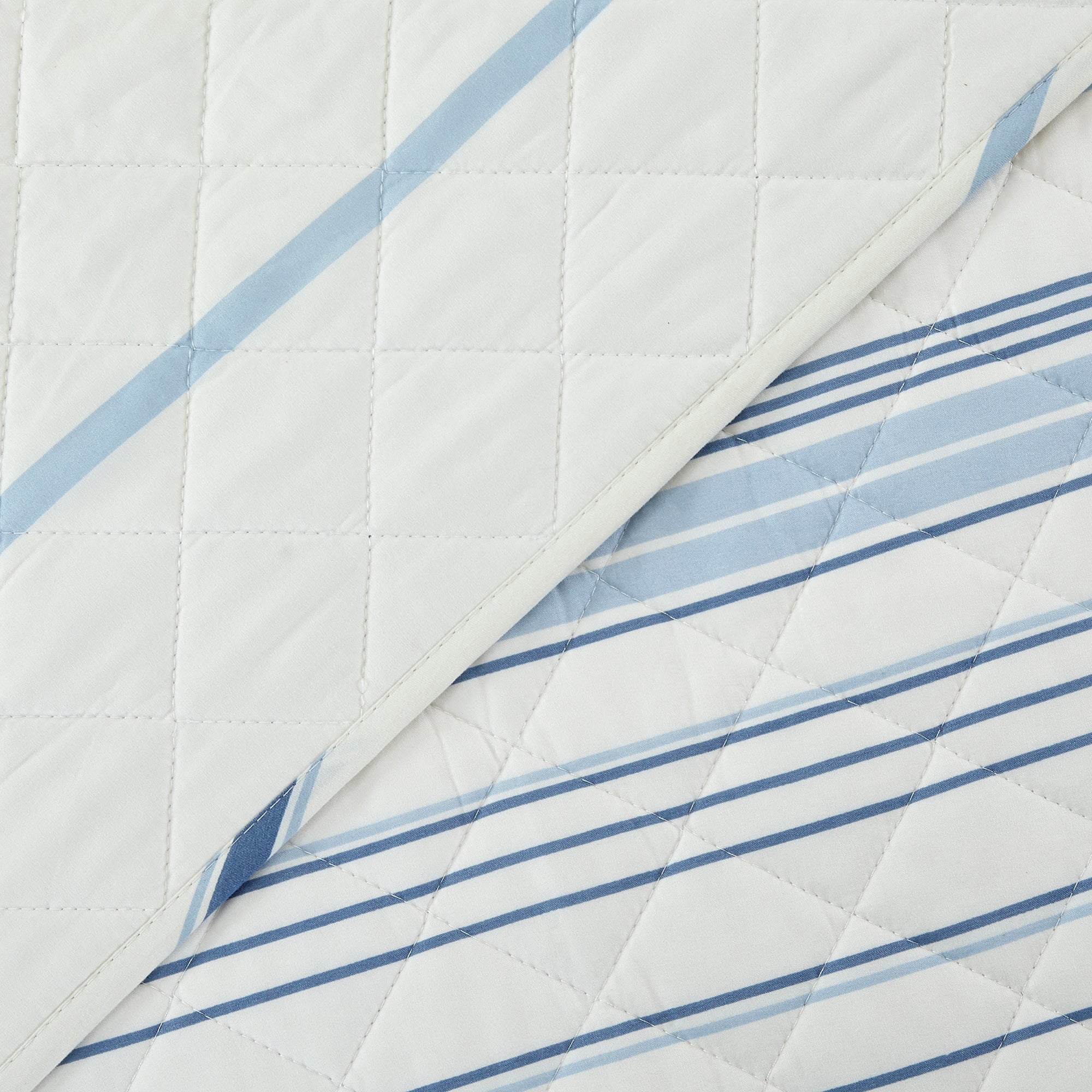 Sofia Collection striped quilt set featuring classic blue and white stripes with a reversible design, shown on beds and in close-up detail views. Soft, lightweight bedding with coordinating shams, styled in a bright and casual bedroom setting.