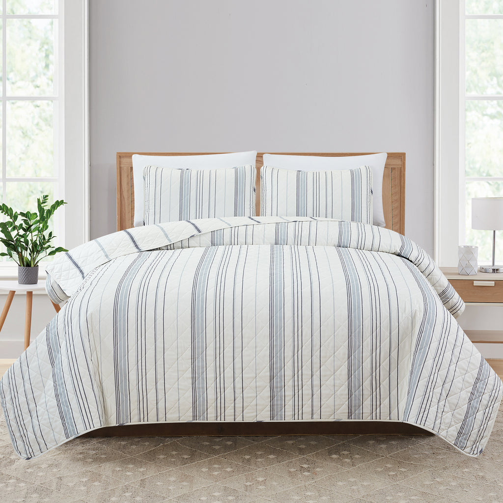 Sofia Collection striped quilt set featuring classic blue and white stripes with a reversible design, shown on beds and in close-up detail views. Soft, lightweight bedding with coordinating shams, styled in a bright and casual bedroom setting.