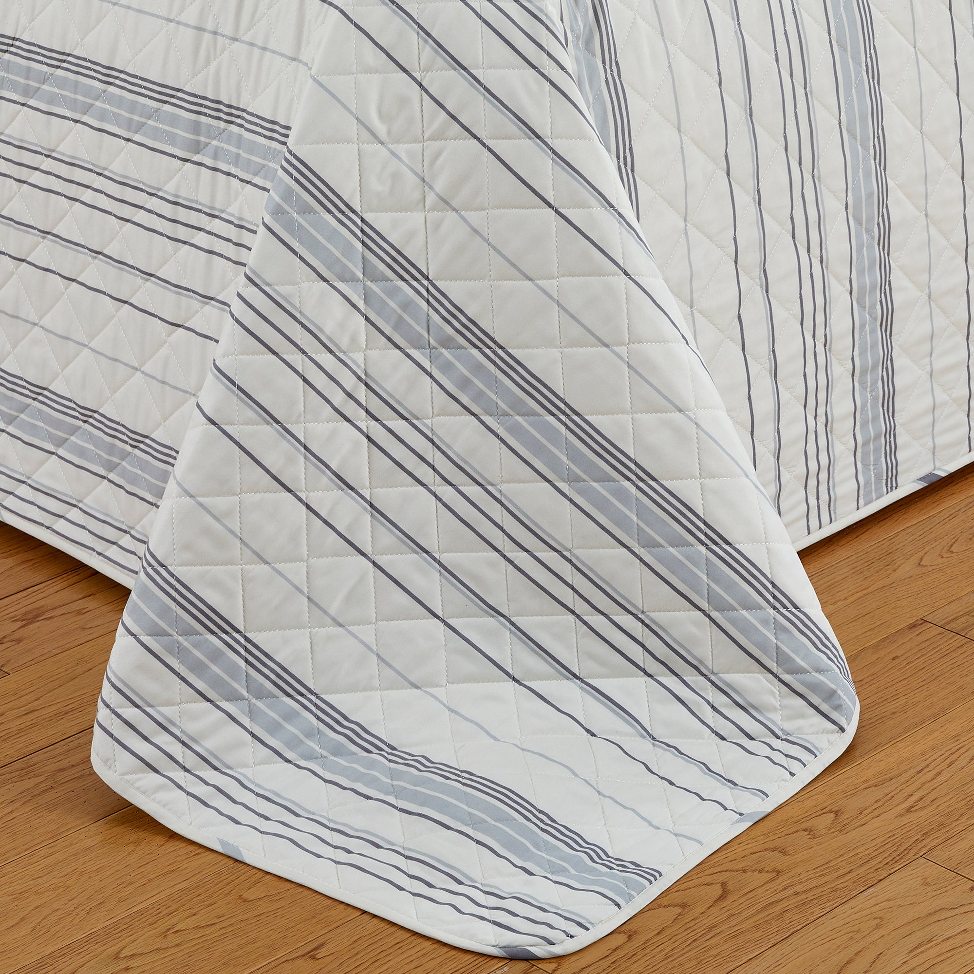 Sofia Collection striped quilt set featuring classic blue and white stripes with a reversible design, shown on beds and in close-up detail views. Soft, lightweight bedding with coordinating shams, styled in a bright and casual bedroom setting.