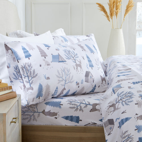 Printed 100% Turkish cotton flannel sheet set featuring assorted winter-inspired patterns, including woodland animals, snowflakes, trees, plaids, and seasonal motifs. Soft, cozy bedding shown in styled bedroom settings with close-up fabric details and folded sheet stacks in multiple designs.