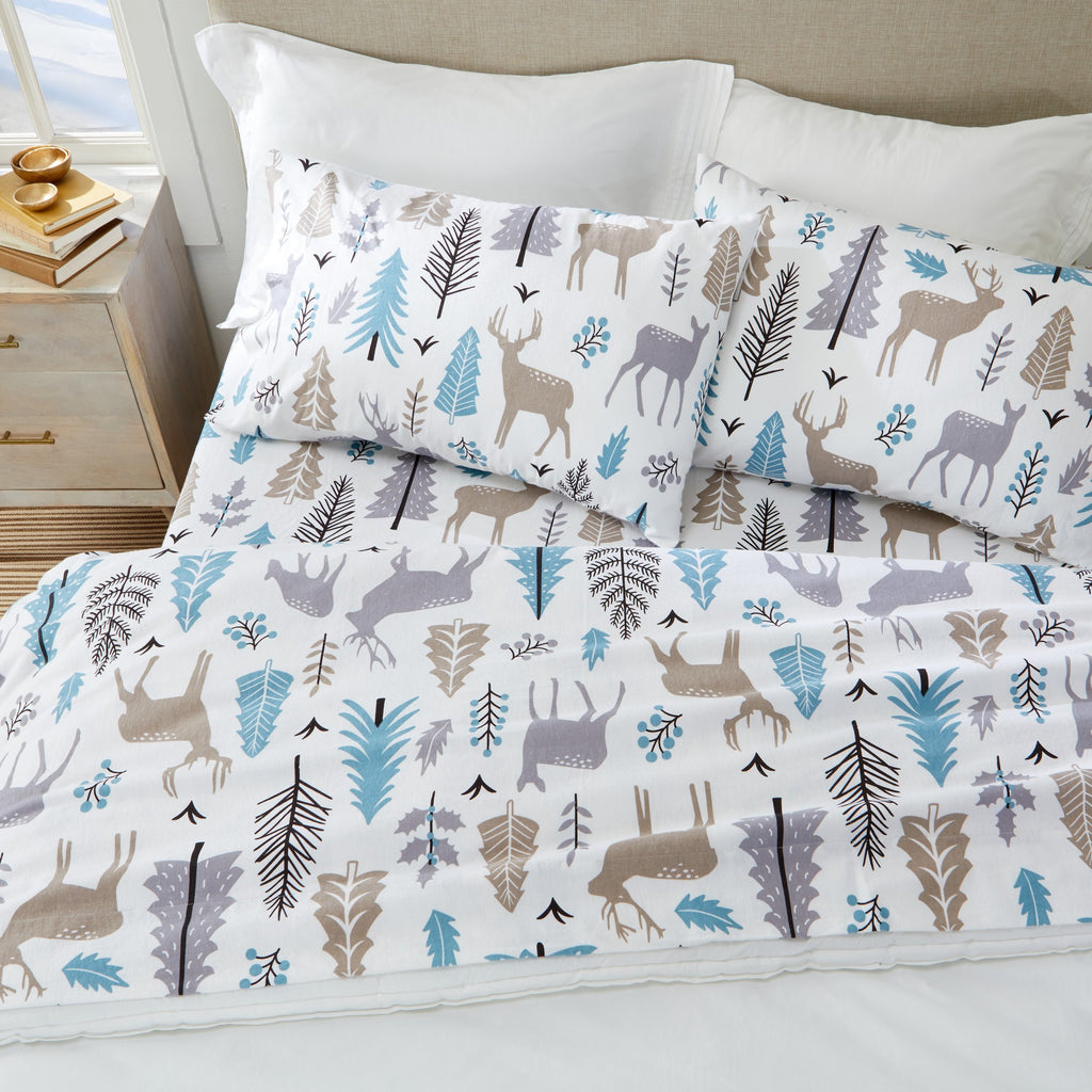 Printed 100% Turkish cotton flannel sheet set featuring assorted winter-inspired patterns, including woodland animals, snowflakes, trees, plaids, and seasonal motifs. Soft, cozy bedding shown in styled bedroom settings with close-up fabric details and folded sheet stacks in multiple designs.