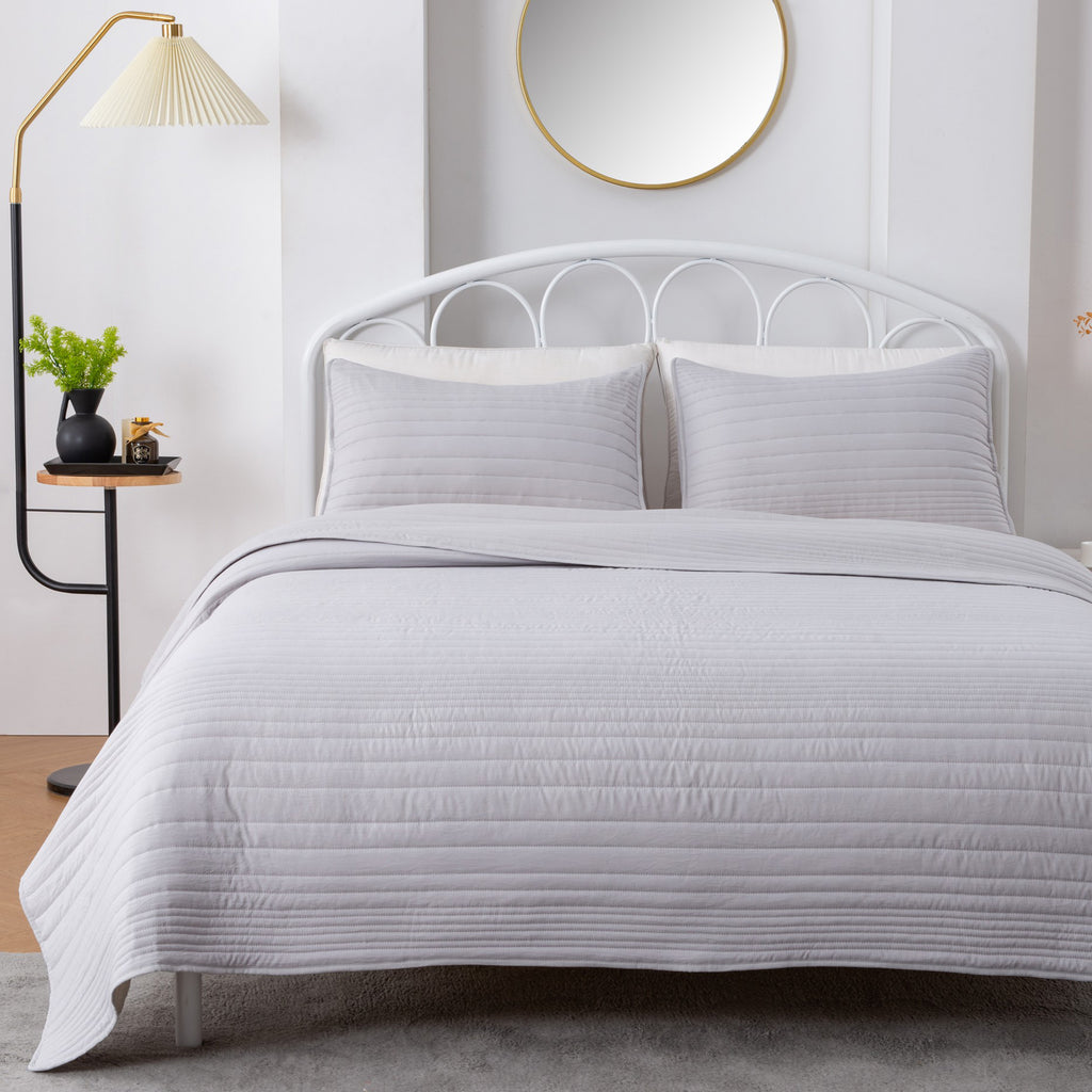 Parker Collection Solid Embroidered Quilt Set by Market & Place featuring soft microfiber construction and elegant channel embroidery. Available in multiple colors with coordinating shams and detailed fabric close-ups, styled in a modern bedroom setting.