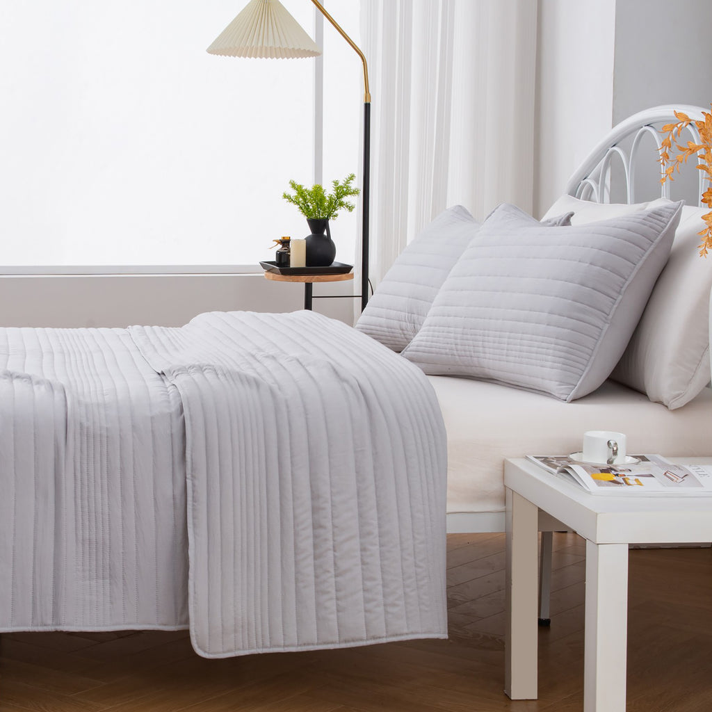 Parker Collection Solid Embroidered Quilt Set by Market & Place featuring soft microfiber construction and elegant channel embroidery. Available in multiple colors with coordinating shams and detailed fabric close-ups, styled in a modern bedroom setting.