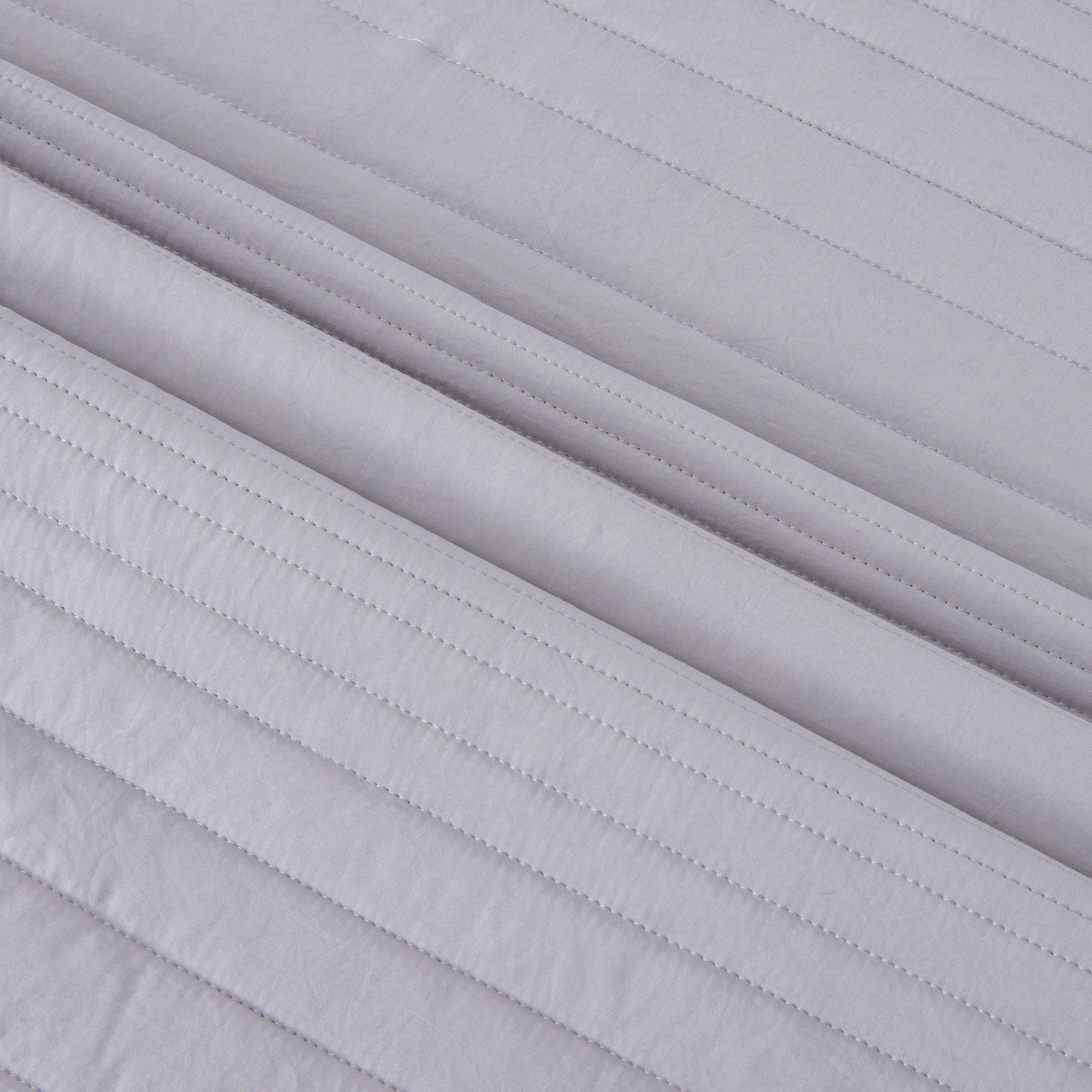 Parker Collection Solid Embroidered Quilt Set by Market & Place featuring soft microfiber construction and elegant channel embroidery. Available in multiple colors with coordinating shams and detailed fabric close-ups, styled in a modern bedroom setting.