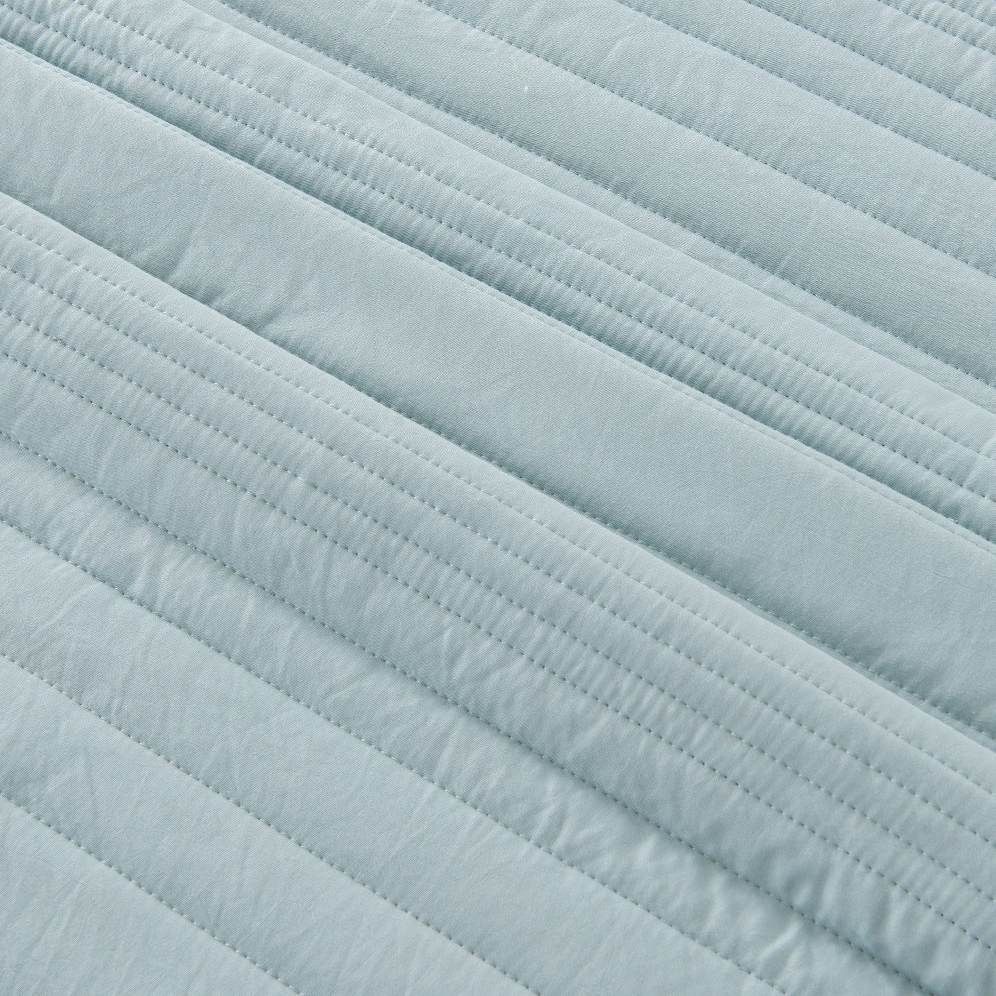 Parker Collection Solid Embroidered Quilt Set by Market & Place featuring soft microfiber construction and elegant channel embroidery. Available in multiple colors with coordinating shams and detailed fabric close-ups, styled in a modern bedroom setting.