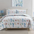 Coastal Collection Reversible Quilt Set by Market & Place featuring soft microfiber construction and coastal-inspired prints, including seashells, starfish, seahorses, coral, and ocean motifs. Coordinating shams and detailed fabric close-ups are shown in a bright bedroom setting, highlighting the reversible design and all-season comfort.