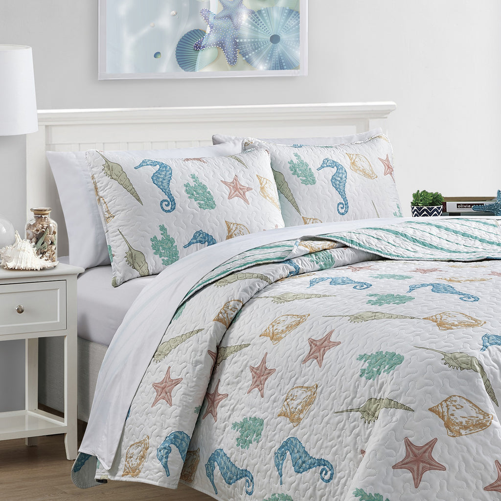 Coastal Collection Reversible Quilt Set by Market & Place featuring soft microfiber construction and coastal-inspired prints, including seashells, starfish, seahorses, coral, and ocean motifs. Coordinating shams and detailed fabric close-ups are shown in a bright bedroom setting, highlighting the reversible design and all-season comfort.