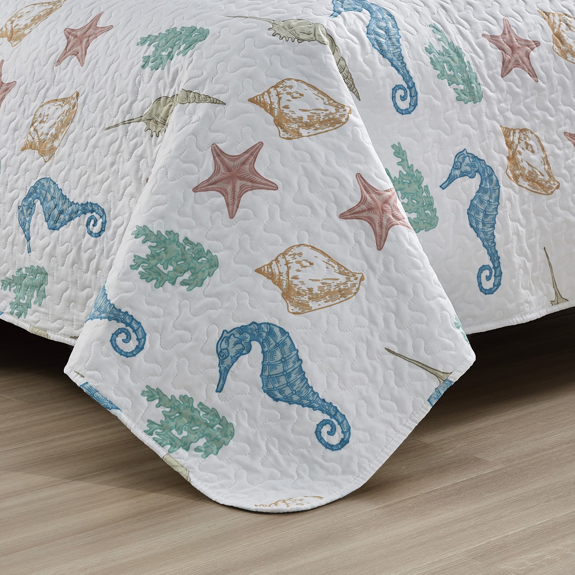 Coastal Collection Reversible Quilt Set by Market & Place featuring soft microfiber construction and coastal-inspired prints, including seashells, starfish, seahorses, coral, and ocean motifs. Coordinating shams and detailed fabric close-ups are shown in a bright bedroom setting, highlighting the reversible design and all-season comfort.