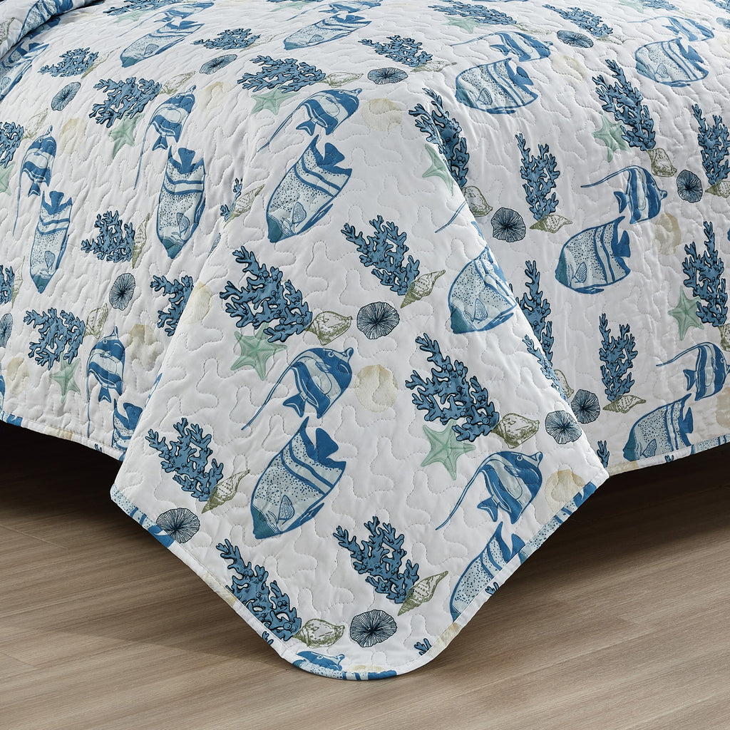 Coastal Collection Reversible Quilt Set by Market & Place featuring soft microfiber construction and coastal-inspired prints, including seashells, starfish, seahorses, coral, and ocean motifs. Coordinating shams and detailed fabric close-ups are shown in a bright bedroom setting, highlighting the reversible design and all-season comfort.