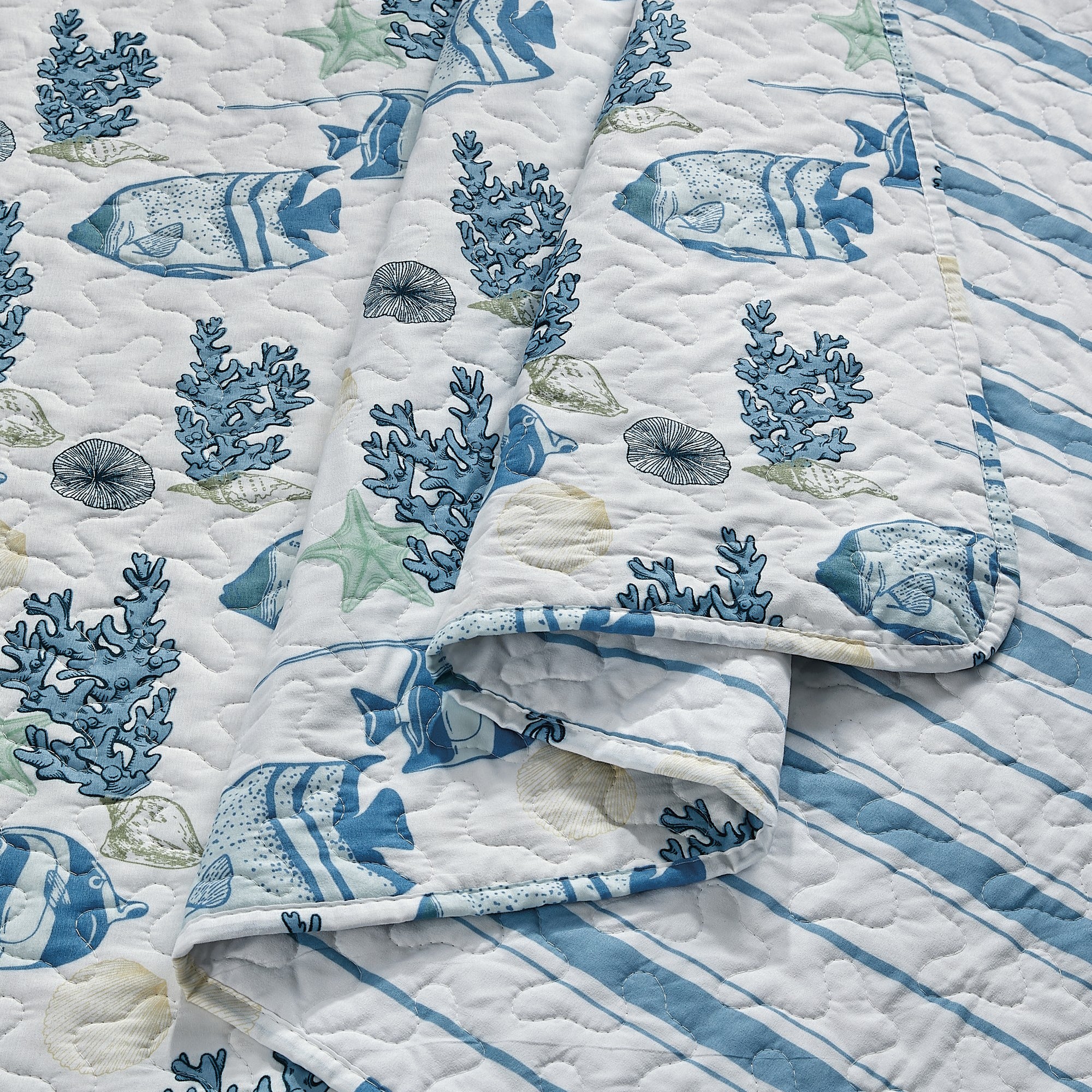 Coastal Collection Reversible Quilt Set by Market & Place featuring soft microfiber construction and coastal-inspired prints, including seashells, starfish, seahorses, coral, and ocean motifs. Coordinating shams and detailed fabric close-ups are shown in a bright bedroom setting, highlighting the reversible design and all-season comfort.