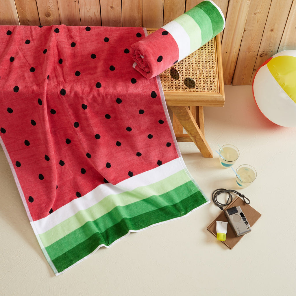 100% cotton velour beach towel featuring a colorful jacquard design, displayed on a wooden deck. Soft, absorbent, and durable, perfect for beach days, poolside lounging, and summer travel.