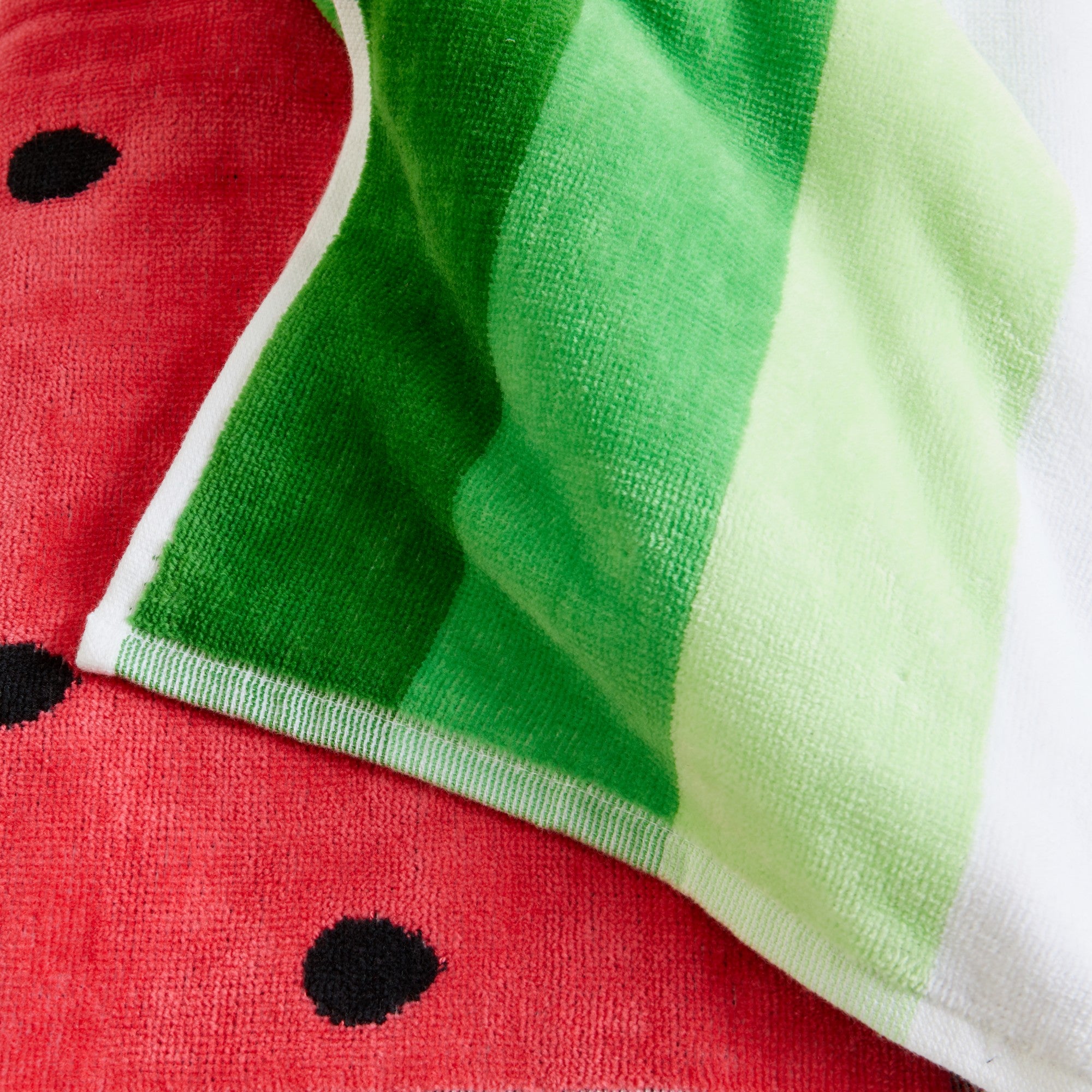 100% cotton velour beach towel featuring a colorful jacquard design, displayed on a wooden deck. Soft, absorbent, and durable, perfect for beach days, poolside lounging, and summer travel.