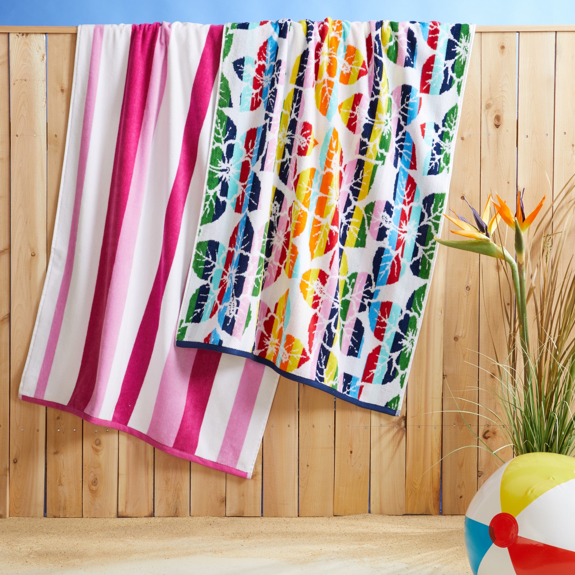 100% cotton velour beach towel featuring a colorful jacquard design, displayed on a wooden deck. Soft, absorbent, and durable, perfect for beach days, poolside lounging, and summer travel.
