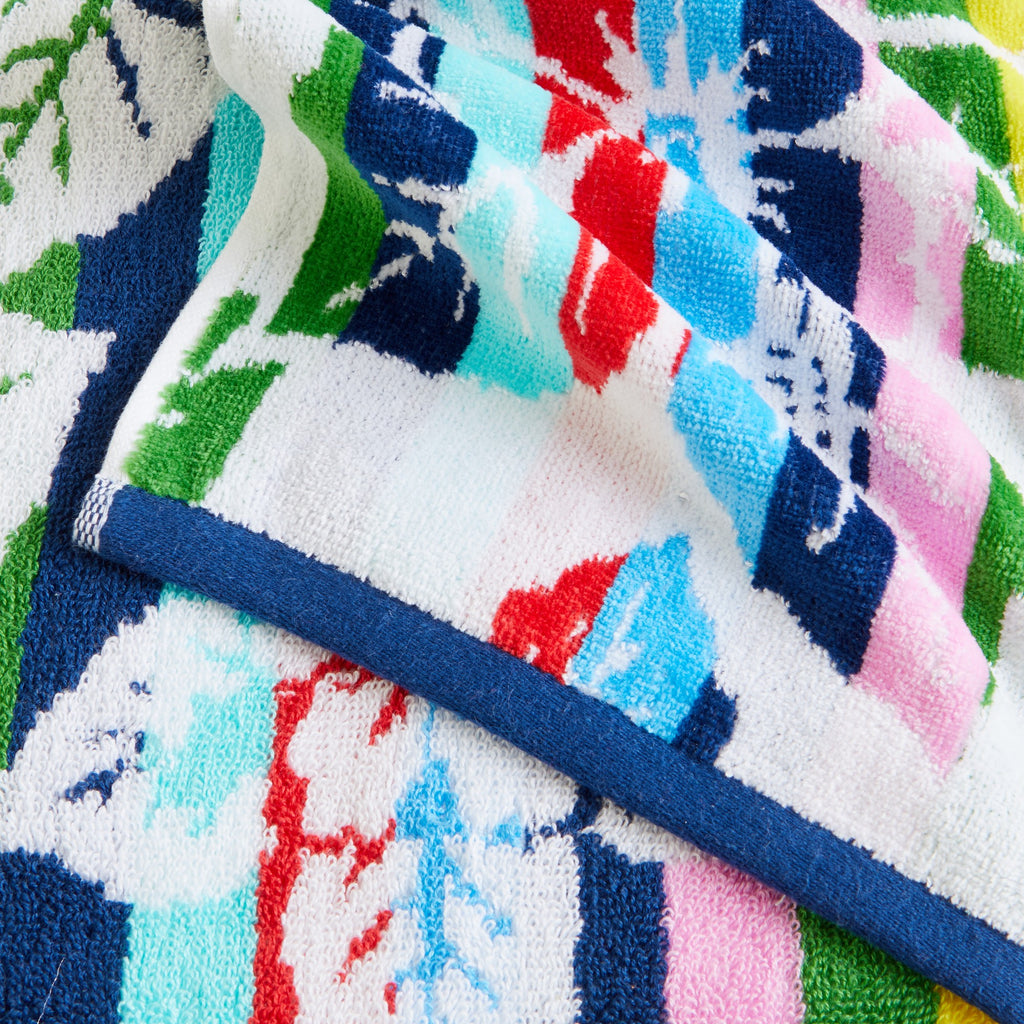 100% cotton velour beach towel featuring a colorful jacquard design, displayed on a wooden deck. Soft, absorbent, and durable, perfect for beach days, poolside lounging, and summer travel.
