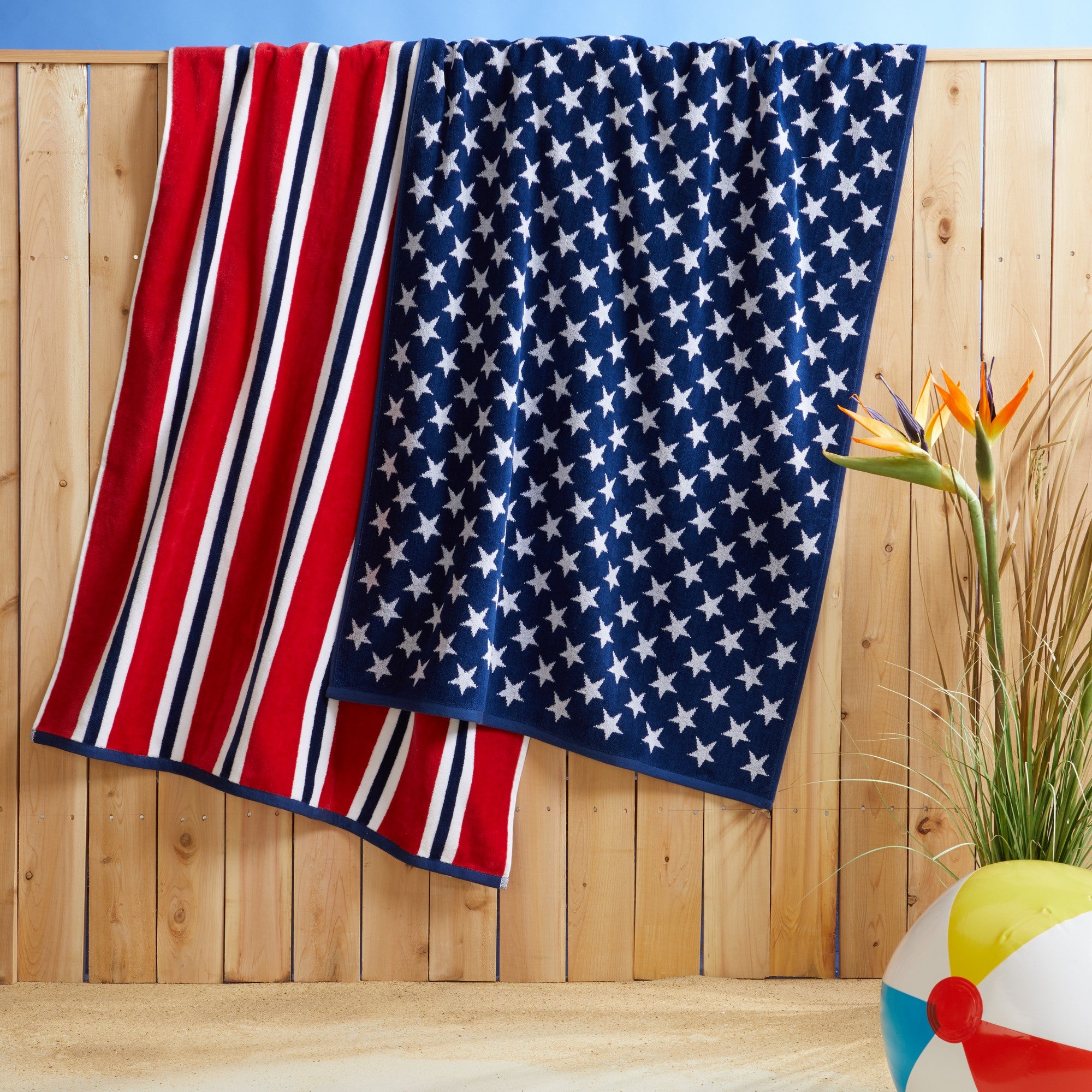 100% cotton velour beach towel featuring a colorful jacquard design, displayed on a wooden deck. Soft, absorbent, and durable, perfect for beach days, poolside lounging, and summer travel.