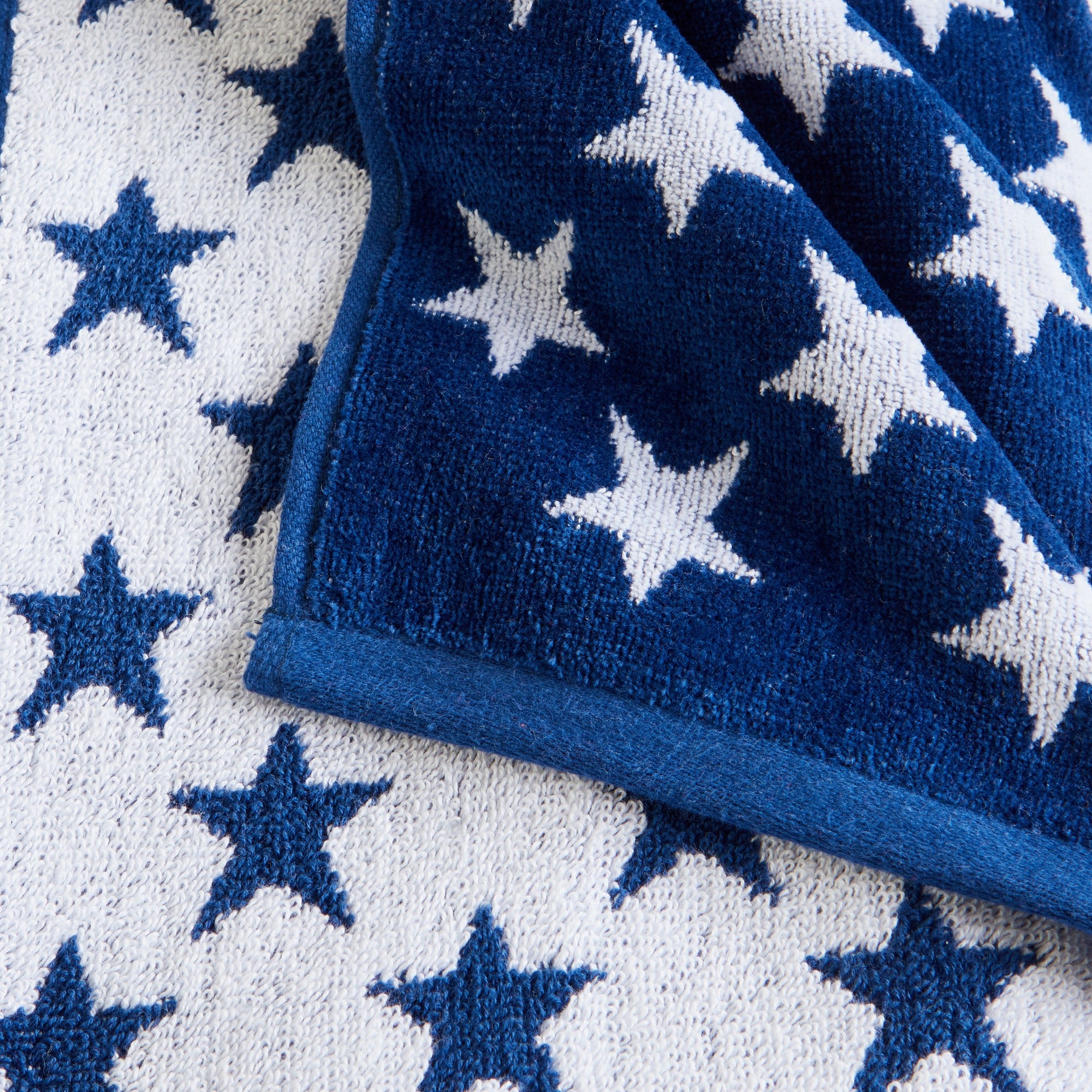 100% cotton velour beach towel featuring a colorful jacquard design, displayed on a wooden deck. Soft, absorbent, and durable, perfect for beach days, poolside lounging, and summer travel.