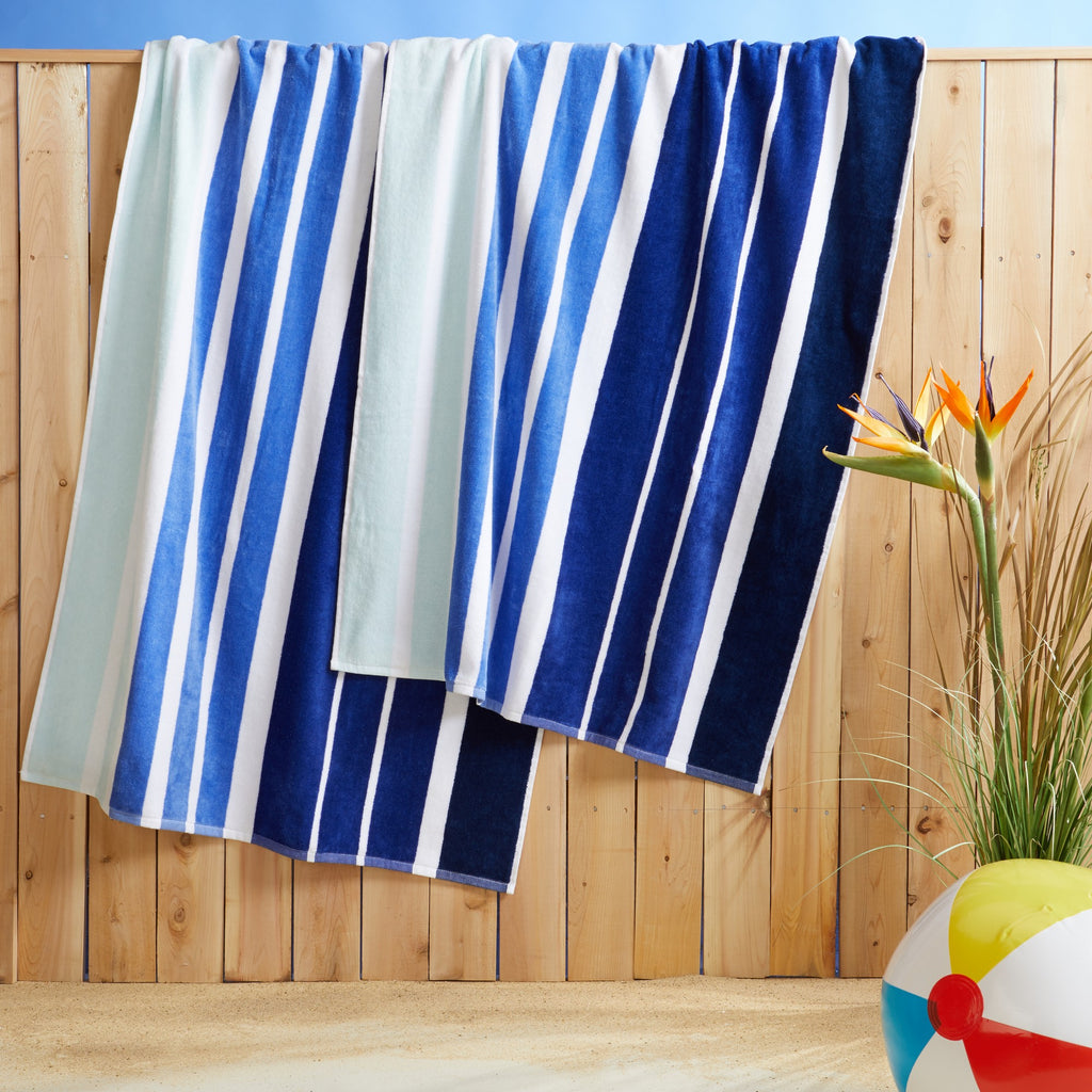 100% cotton velour beach towel featuring a colorful jacquard design, displayed on a wooden deck. Soft, absorbent, and durable, perfect for beach days, poolside lounging, and summer travel.