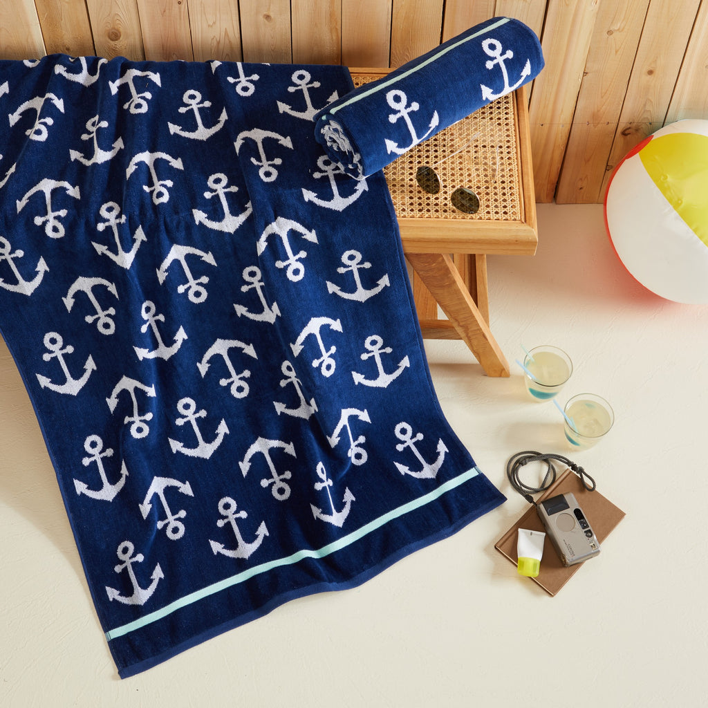 100% cotton velour beach towel featuring a colorful jacquard design, displayed on a wooden deck. Soft, absorbent, and durable, perfect for beach days, poolside lounging, and summer travel.