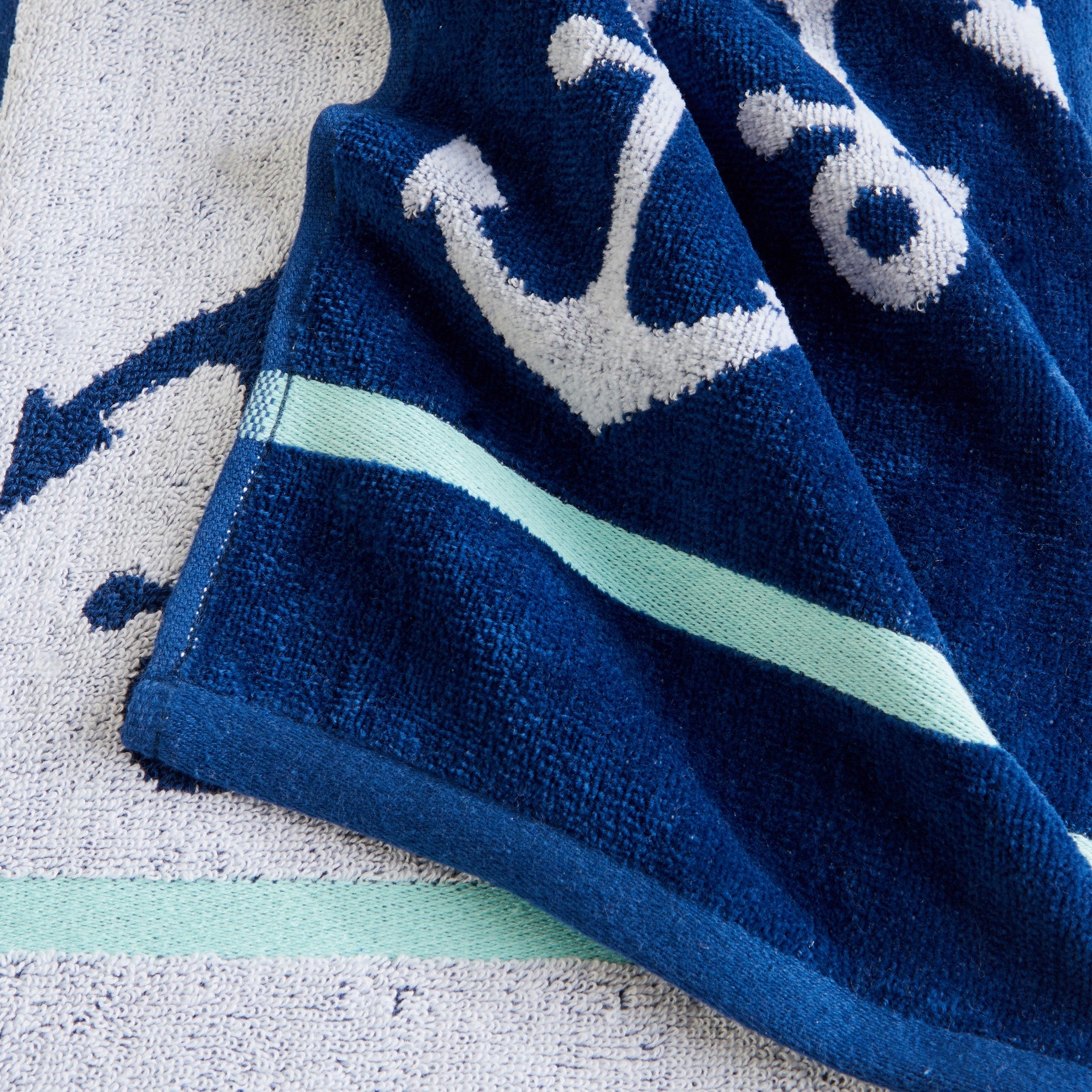 100% cotton velour beach towel featuring a colorful jacquard design, displayed on a wooden deck. Soft, absorbent, and durable, perfect for beach days, poolside lounging, and summer travel.