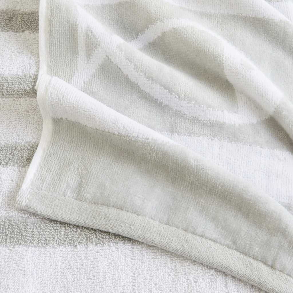 100% cotton velour beach towel featuring a colorful jacquard design, displayed on a wooden deck. Soft, absorbent, and durable, perfect for beach days, poolside lounging, and summer travel.