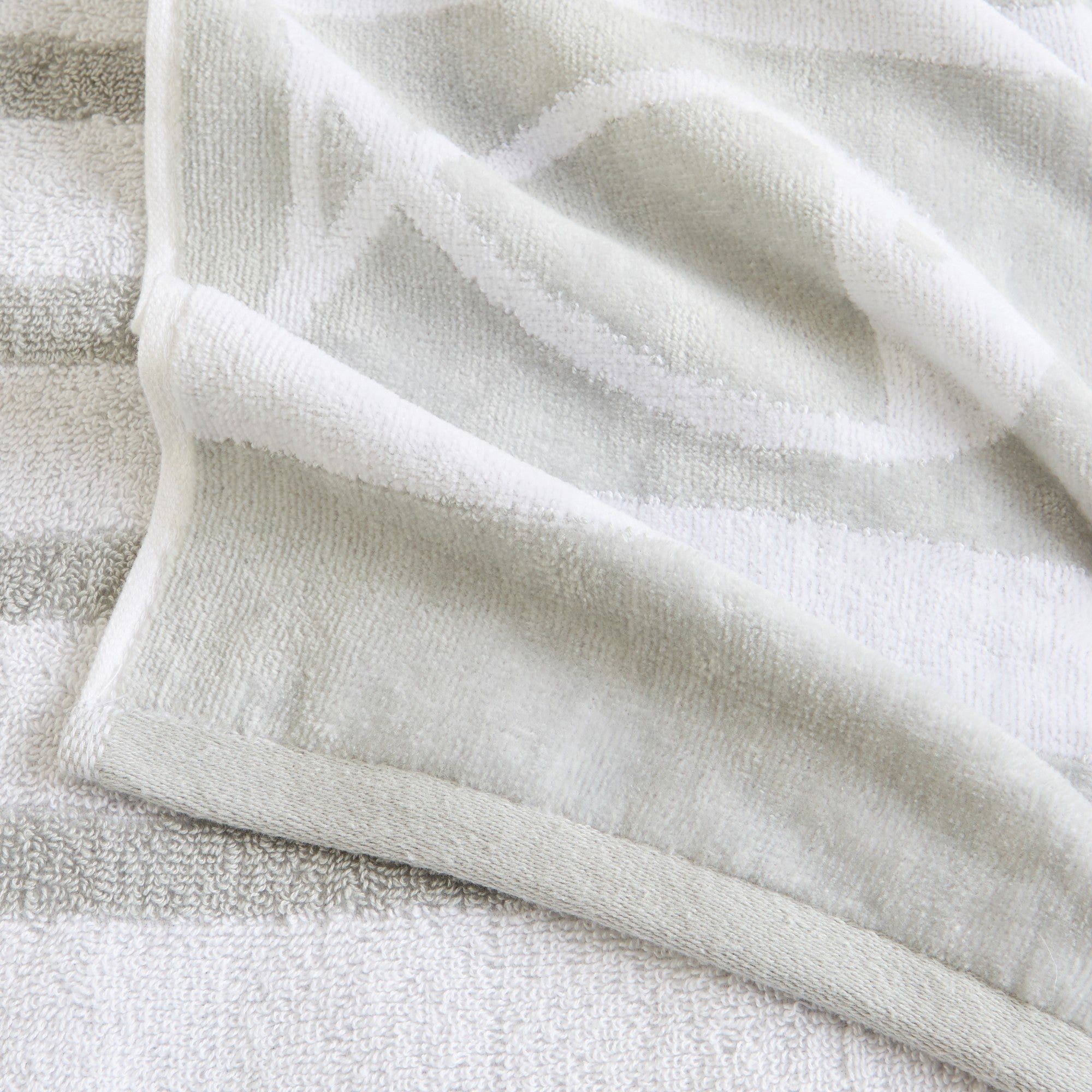 100% cotton velour beach towel featuring a colorful jacquard design, displayed on a wooden deck. Soft, absorbent, and durable, perfect for beach days, poolside lounging, and summer travel.